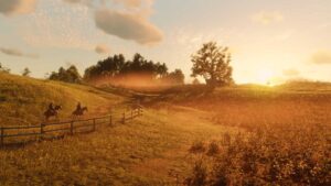 Two riders gallop along a dirt path through golden fields at sunset in Red Dead Redemption 2.